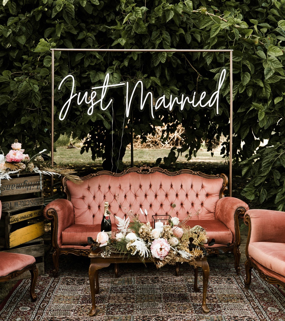 Styling details of a wedding reception, including neon sign and velvet lounge.